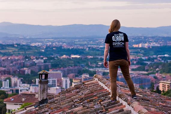 学生穿着t恤，上面写着“抓住世界的犄角”. “留学”站在屋顶上眺望村庄